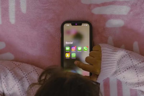 Criança mexendo no celular com as redes sociais visíveis no aparelho. — Foto: Unsplash/Sanket Mishra