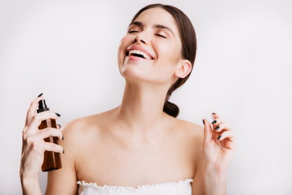 satisfied-brunette-girl-after-shower-sprays-mist-body-skin-woman-smiling-isolated-wall
